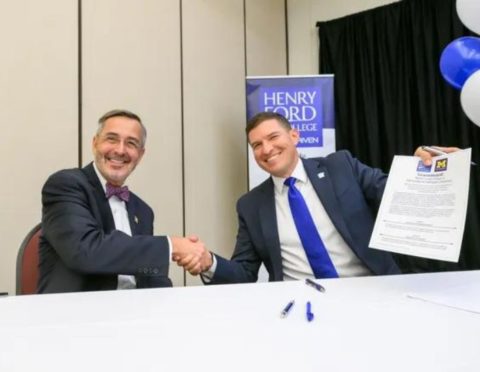 Domenico Grasso and Russ Kavalhuna shaking hands after signing an agreement that guarantees admission by Henry Ford College transfer students to UM-Dearborn.