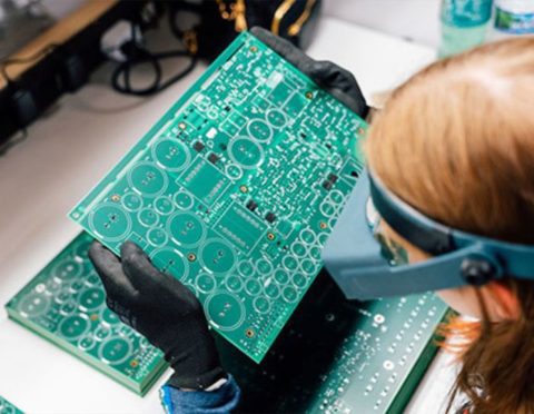 A Michigan Tech engineering student inspects a circuit board as part of the university’s partnership with Calumet Electronics.