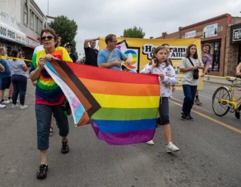 Former councilmember of Hamtramck Catrina Stackpoole holds an LGBTQ Progress Pride Flag during the Labor Day parade in Hamtramck.