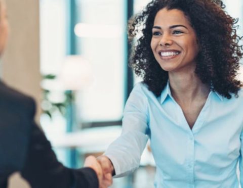 A Black woman shaking hands with an interviewer.