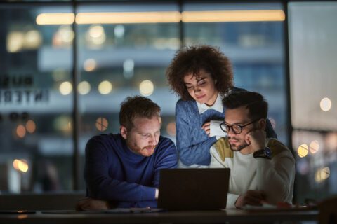 Three workers working late in an office.