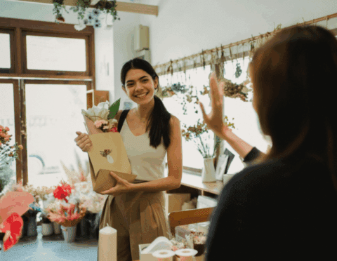 small business confidence improves - us chamber - florist small business owner with customer holding bouquet