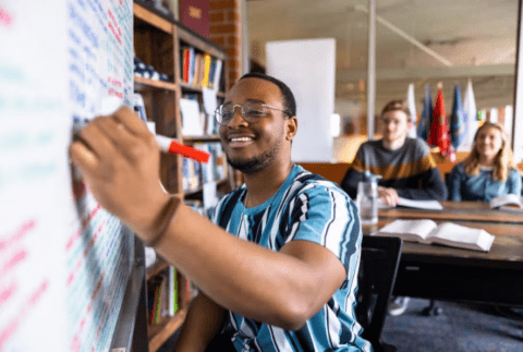 man smiling and writing on a whiteboard