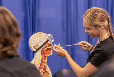 Girl participating in hands-on demonstration with manikin at 2026 Health Careers Expo