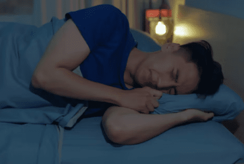 a man lying down gripping his pillow in bed