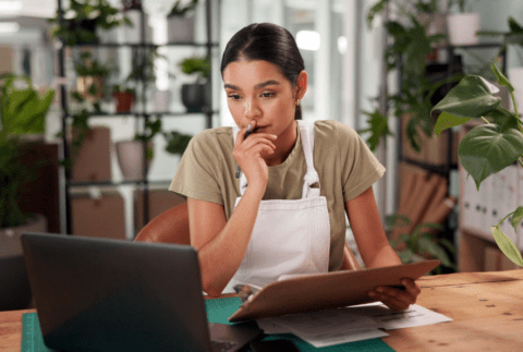 a small business owner looking at her laptop and holding her tablet