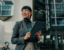 Happy businesswoman holding digital tablet looking away while standing outside modern office building