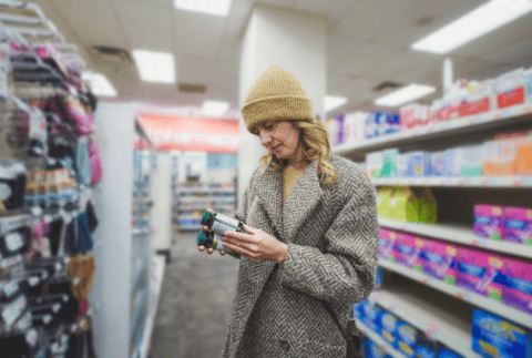 Woman shopping for multivitamins at pharmacy store