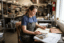a small business owner reviews vendor invoices and a ledger at a desk