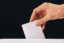 Close-up of human hand casting and inserting a vote and choosing and making a decision what he wants in polling box